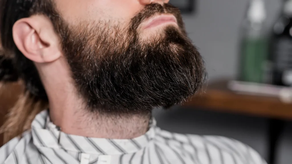 Homem de perfil exibindo uma barba cheia e bem cuidada, um dos mais populares estilos de barba, com destaque para o volume e o contorno definido no queixo.