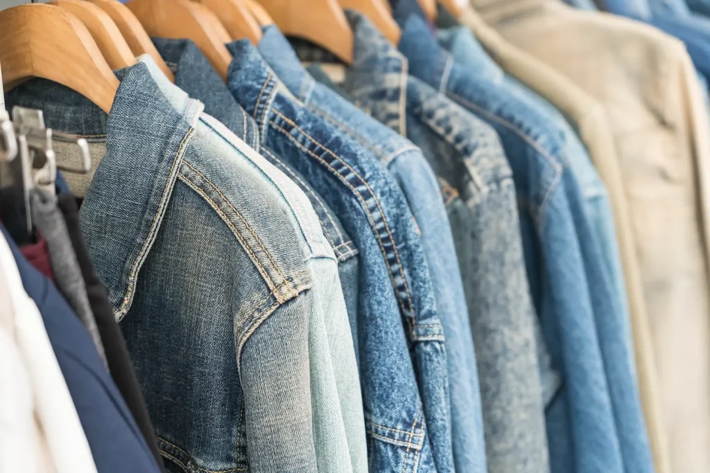 Arara com jaquetas jeans em tons variados de azul, destacando textura e acabamento do denim como exemplo de tipos de tecido.